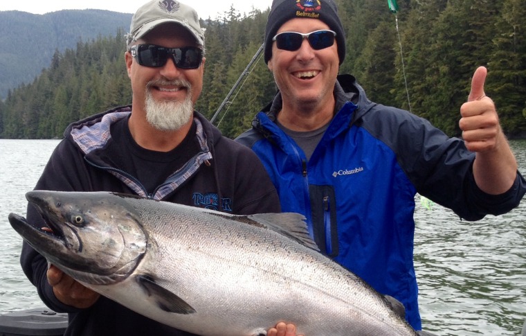 Happy customer in Alaska poses with caught Salmon